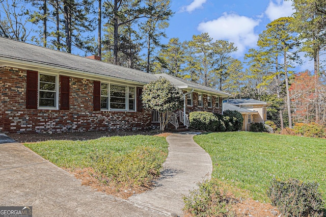 ranch-style house featuring brick siding, a front lawn, and a chimney