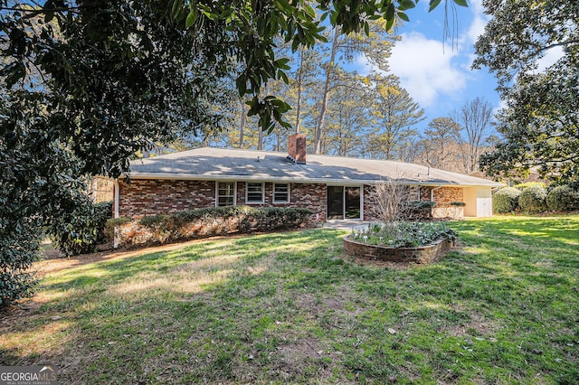 back of property with a yard, brick siding, and a chimney