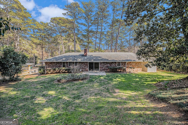 rear view of house featuring brick siding and a yard