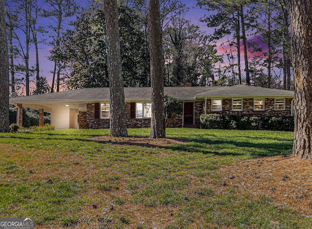 view of front of house featuring brick siding, a carport, and a front yard