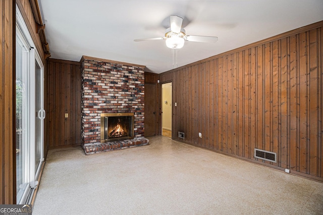 unfurnished living room featuring a brick fireplace, visible vents, and wood walls