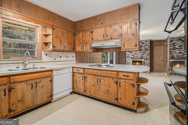 kitchen featuring white appliances, a fireplace, a sink, and under cabinet range hood