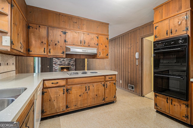 kitchen with gas stovetop, light countertops, dobule oven black, a peninsula, and under cabinet range hood