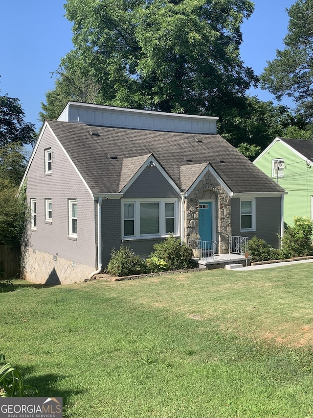 view of front of home with stone siding, brick siding, roof with shingles, and a front yard