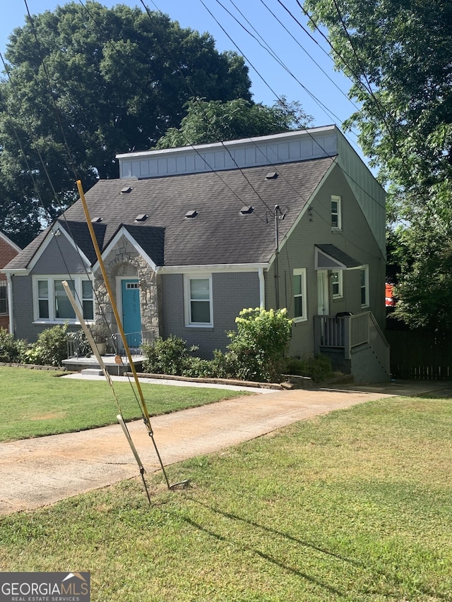 view of front of property with stone siding, roof with shingles, and a front yard