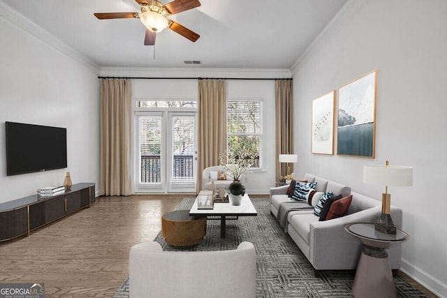 living room with ornamental molding, visible vents, baseboards, and wood finished floors