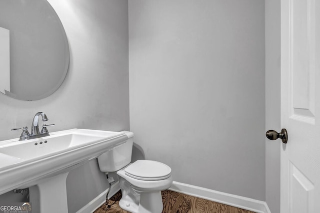 bathroom with toilet, a sink, baseboards, and wood finished floors