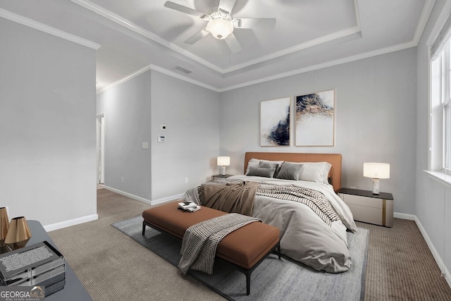 carpeted bedroom with a tray ceiling, visible vents, crown molding, and baseboards