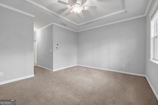 empty room featuring baseboards, carpet, a raised ceiling, and crown molding