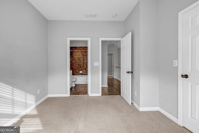 unfurnished bedroom with carpet floors, ensuite bath, visible vents, and baseboards