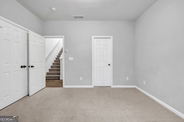 unfurnished bedroom featuring carpet floors, baseboards, visible vents, and a closet