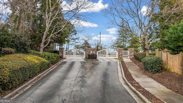 view of road with a gate, sidewalks, curbs, and a gated entry