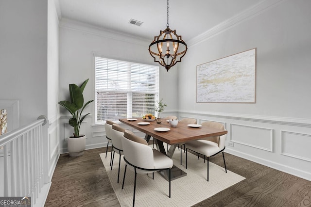 dining space featuring visible vents, dark wood finished floors, crown molding, a decorative wall, and a notable chandelier