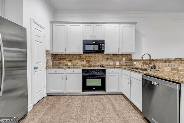 kitchen with black appliances, ornamental molding, a sink, and light wood-style floors