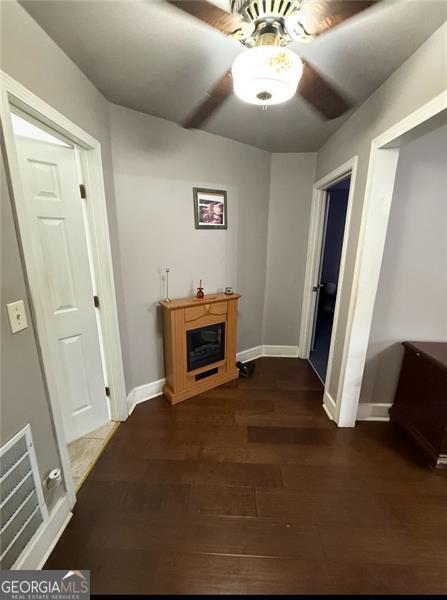 corridor featuring baseboards, visible vents, and dark wood-style flooring