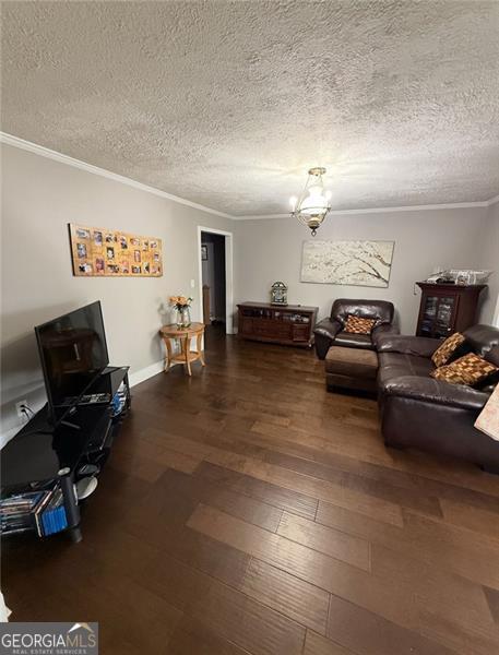 living area with a textured ceiling, dark wood-style flooring, and crown molding