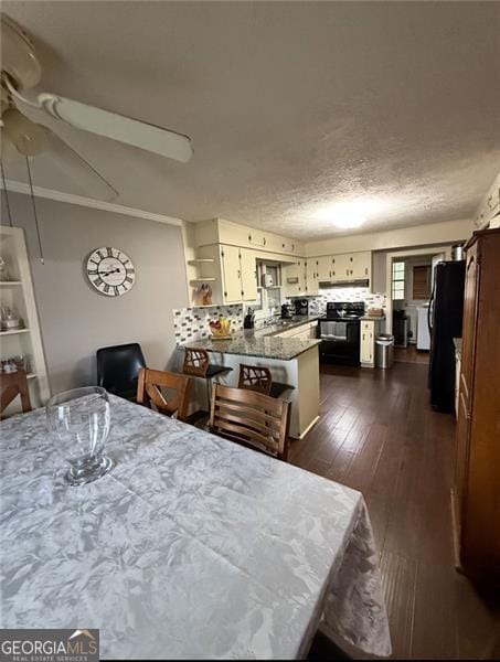 dining room featuring dark wood-style floors, ceiling fan, a textured ceiling, and crown molding