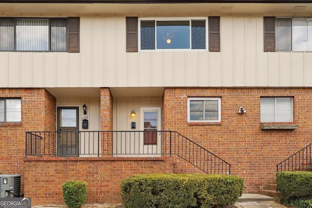 townhome / multi-family property with stairs, central AC, and brick siding