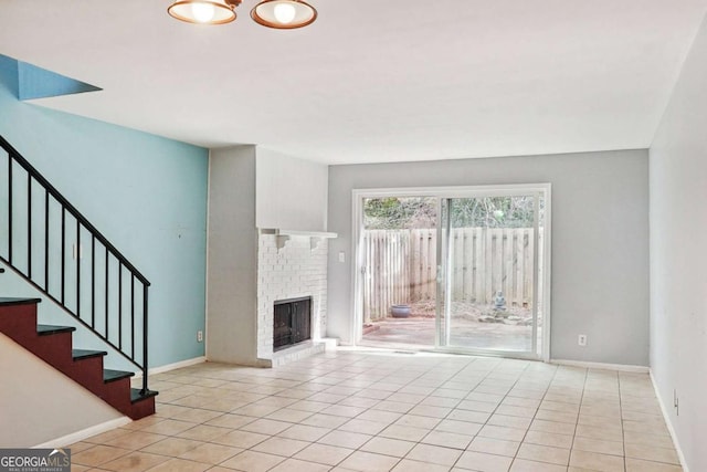 unfurnished living room featuring light tile patterned floors, a fireplace, baseboards, and stairs