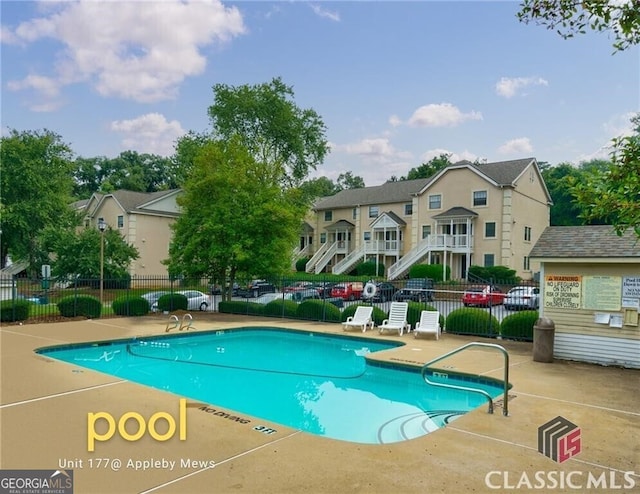 community pool with a patio area and fence