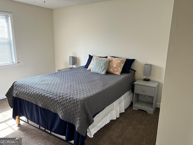 bedroom featuring dark carpet and a textured ceiling