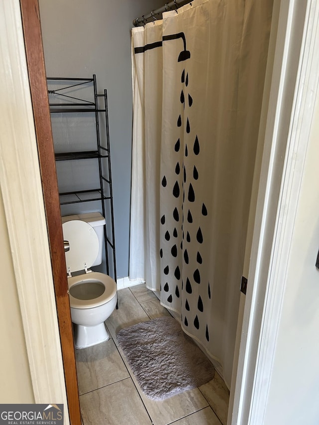 bathroom featuring toilet, a shower with curtain, and tile patterned flooring