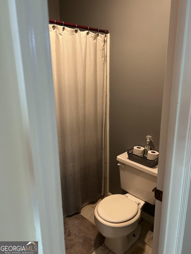 bathroom with a shower with shower curtain, toilet, and tile patterned floors