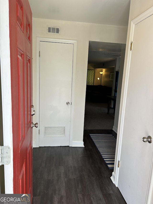 hall with dark wood-style floors, baseboards, and visible vents