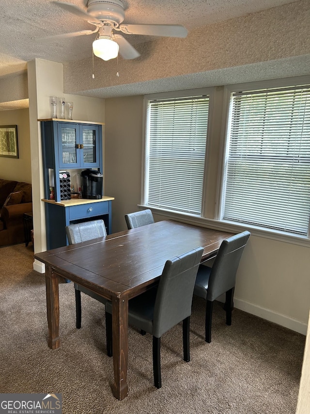 dining area featuring a textured ceiling, carpet flooring, a ceiling fan, and baseboards