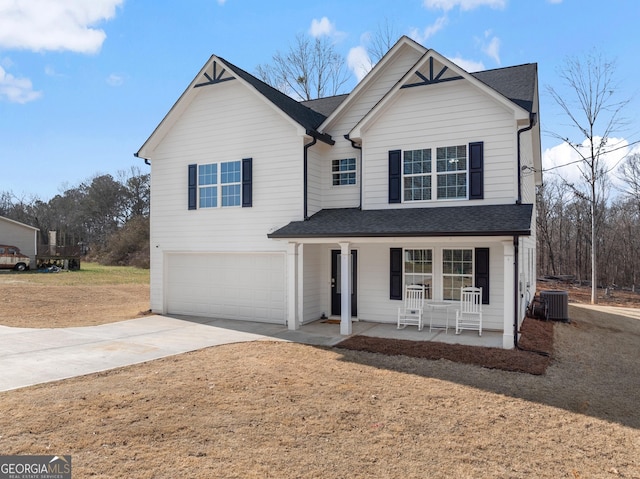 traditional home with central air condition unit, covered porch, an attached garage, driveway, and a front lawn