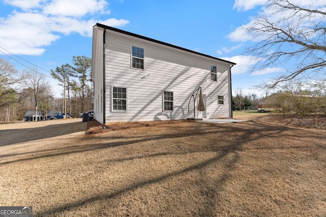 back of house with driveway and a yard