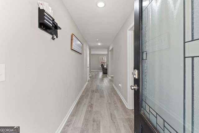 hall featuring light wood-style flooring, baseboards, and recessed lighting