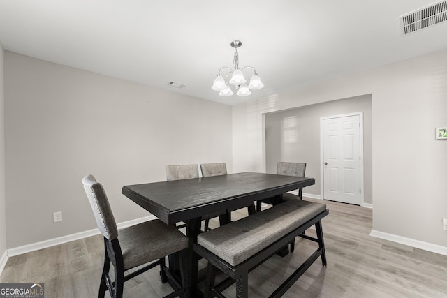 dining room featuring a notable chandelier, light wood-type flooring, visible vents, and baseboards