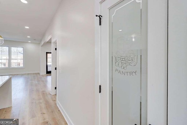 corridor with baseboards, light wood finished floors, and recessed lighting