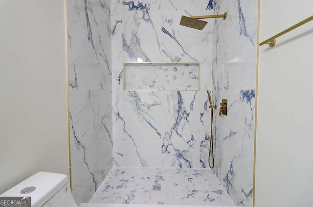 bathroom featuring toilet and a marble finish shower