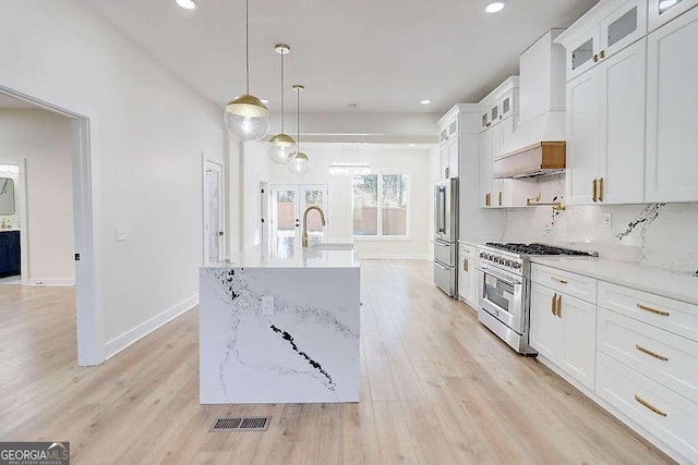 kitchen featuring glass insert cabinets, white cabinets, premium appliances, and decorative light fixtures