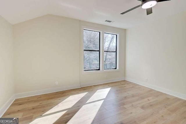 empty room with lofted ceiling, a ceiling fan, baseboards, visible vents, and light wood-style floors