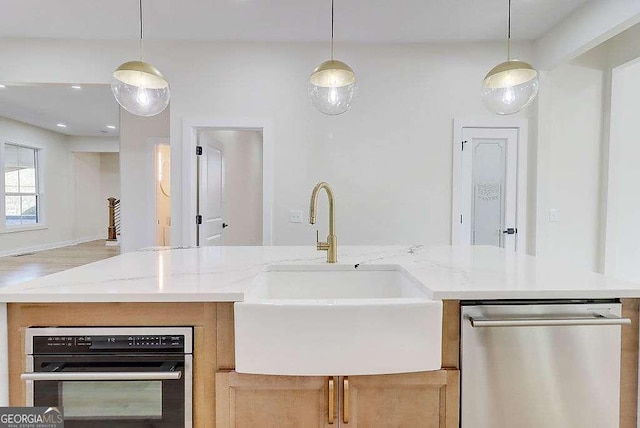 kitchen with a sink, dishwasher, and hanging light fixtures