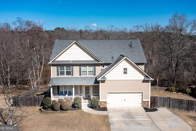 view of front of property featuring driveway, stone siding, roof with shingles, covered porch, and fence