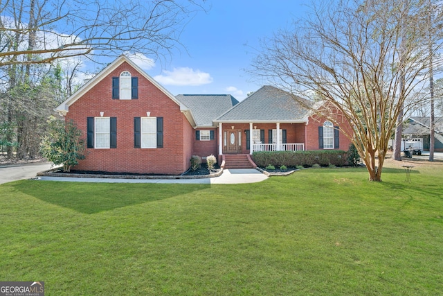 view of front facade featuring covered porch, brick siding, a front yard, and a shingled roof