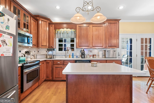 kitchen with crown molding, stainless steel appliances, light countertops, hanging light fixtures, and glass insert cabinets