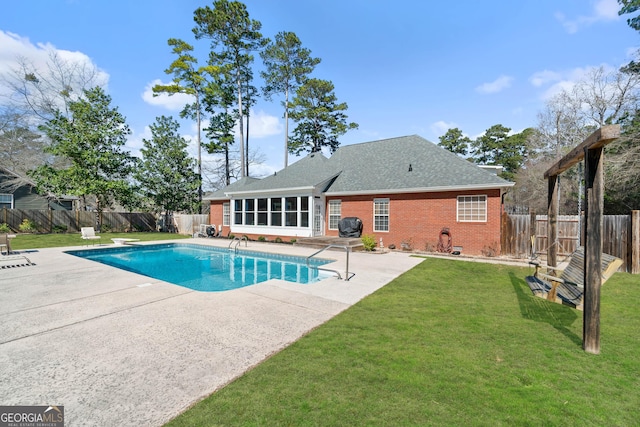 view of pool with a fenced backyard, a sunroom, a lawn, a fenced in pool, and a patio area