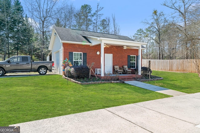 view of front facade with an attached garage, covered porch, fence, a front lawn, and brick siding