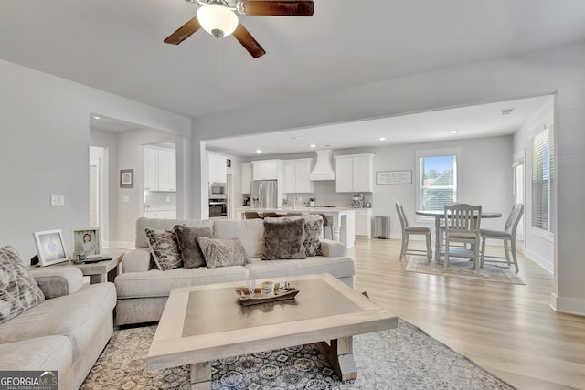 living room with ceiling fan, recessed lighting, light wood-style flooring, and baseboards