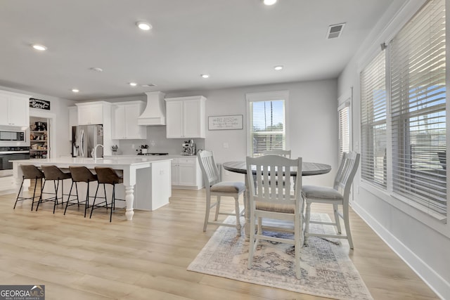 dining room featuring light wood finished floors, baseboards, visible vents, and recessed lighting