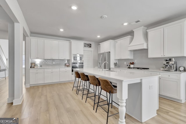 kitchen with appliances with stainless steel finishes, custom exhaust hood, and white cabinets