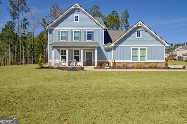 view of front of property featuring a shingled roof, covered porch, a front lawn, board and batten siding, and brick siding