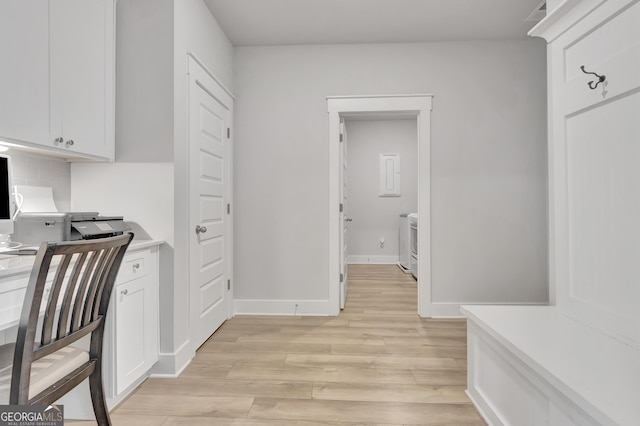 interior space featuring built in desk, washer / dryer, light wood-style flooring, and baseboards