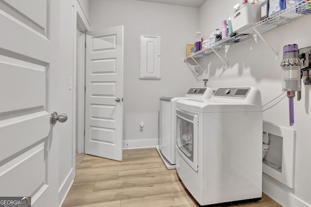 laundry room with light wood finished floors, washing machine and clothes dryer, laundry area, electric panel, and baseboards