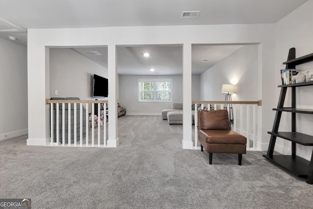 living area with light colored carpet, baseboards, visible vents, and an upstairs landing